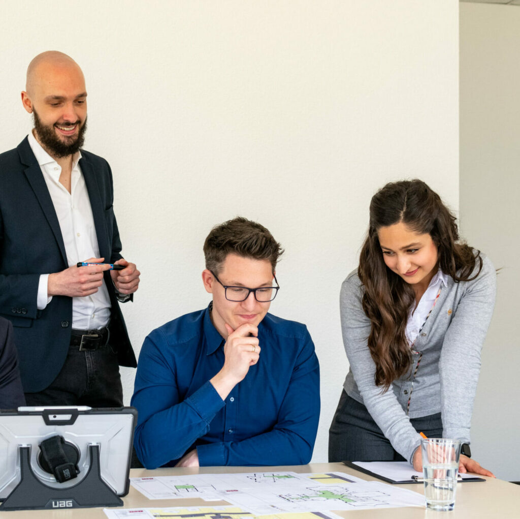 Die Mitarbeiter des BSB-Kröger-Teams besprechen am Tisch Arbeitsunterlagen und Pläne, während sie Dokumente durchsehen und Notizen machen.
